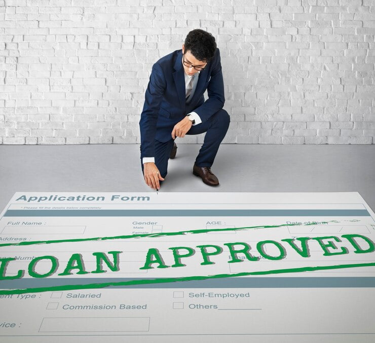 Businessman kneeling in front of approved loan application form